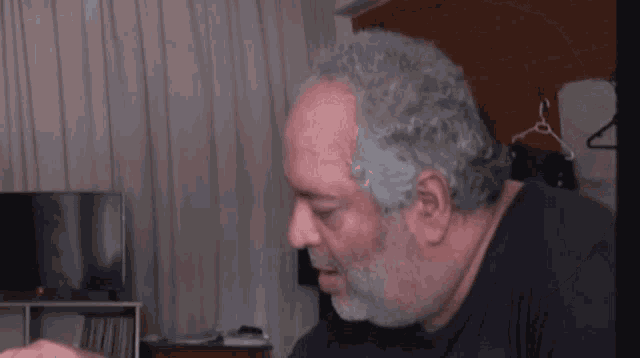 a man with a beard is sitting in front of a television .
