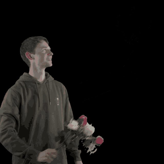 a man wearing a hoodie with a skull on it is holding a bunch of stuffed animals