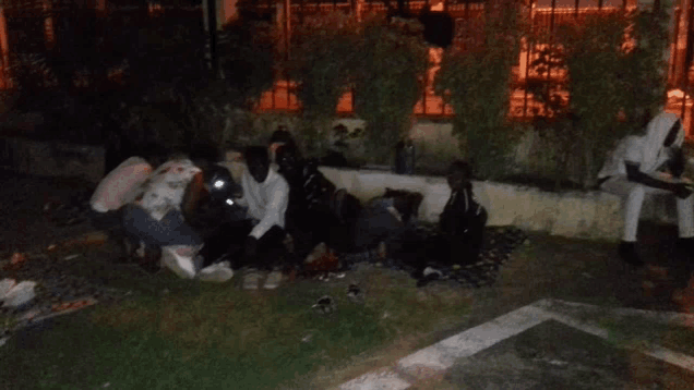 a group of people are sitting on the grass in a dark area