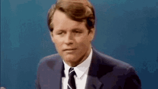 a man in a suit and tie is making a funny face while talking .