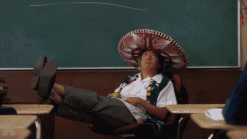 a man wearing a sombrero sits in a chair in front of a chalkboard