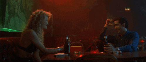 a man and a woman sit at a table in a bar