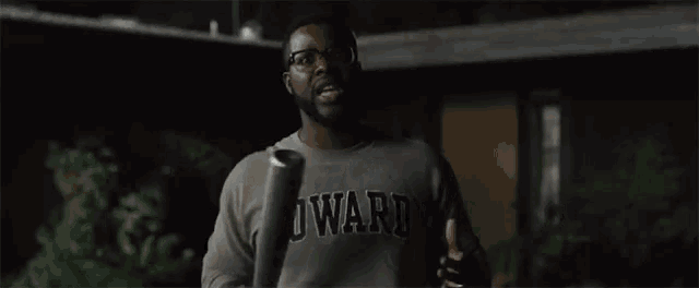 a man wearing a howard shirt holds a bat