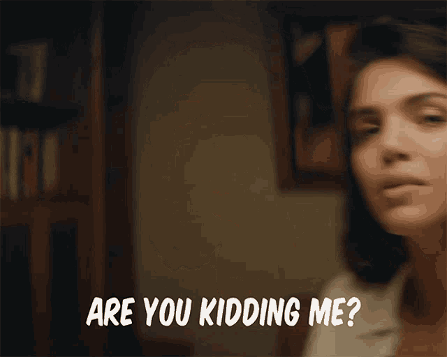 a woman says are you kidding me in front of a bookcase