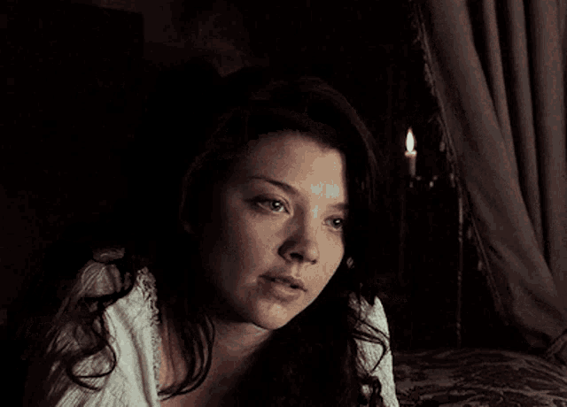 a close up of a woman 's face with a candle behind her