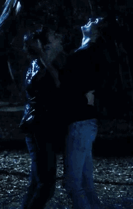 a man and a woman are hugging in the dark in the rain .