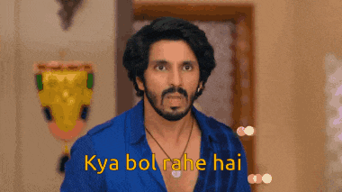 a man with a beard is wearing a blue shirt and a necklace and says kya bol rahe hai