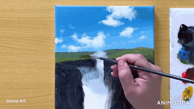 a painting of a waterfall is being painted by a person