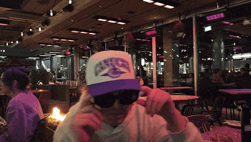 a man wearing sunglasses and a white hat with a purple eagle on it