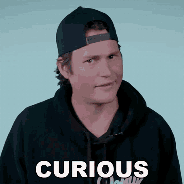 a man wearing a hat and a black hoodie with the word curious written on it