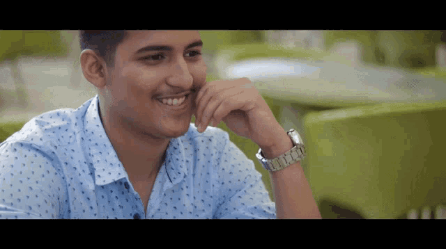 a young man wearing a blue shirt and a silver watch