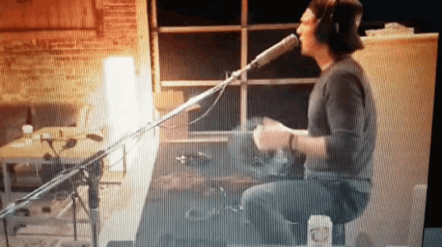 a man is singing into a microphone while playing a drum set