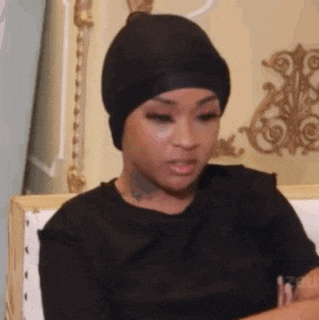 a woman is sitting on a couch wearing a black hat and a black shirt .