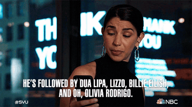 a woman is looking at her phone with the words he 's followed by dua lipa lizzo billie eilish