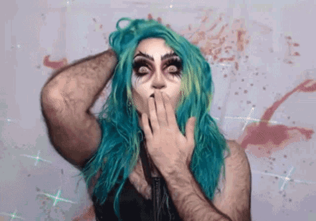 a woman with blue hair and makeup is covering her mouth