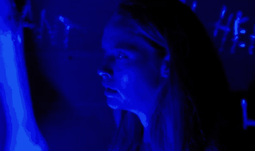 a woman is looking at a computer screen in a dark room with blue lights .