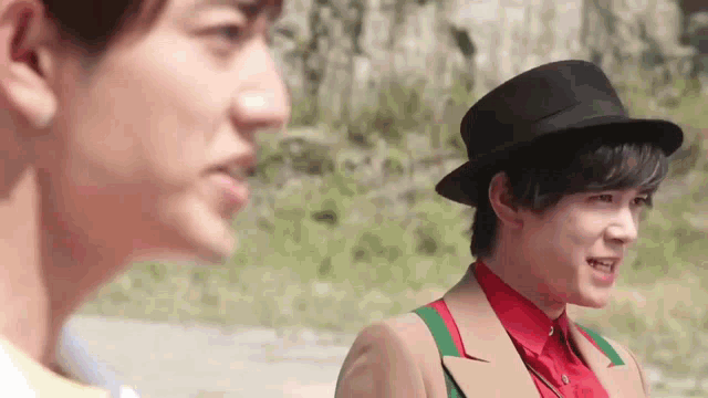 two young men wearing hats are standing next to each other and looking at each other .