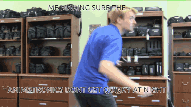 a man in a blue shirt is dancing in front of a display of camera bags
