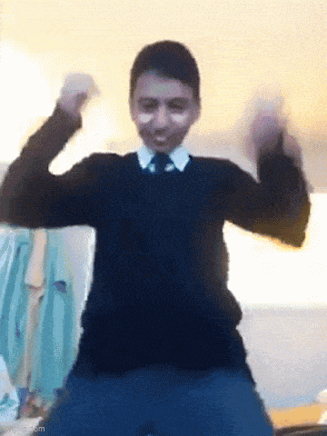 a young boy in a black sweater and tie is dancing in a room .