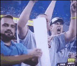 a group of men are holding up their arms in the air while watching a game