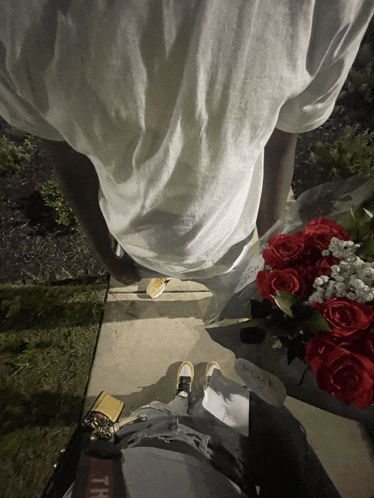 a person standing next to a bouquet of red roses and a wallet that says th