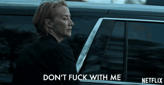 a woman standing next to a car that says " do n't fuck with me " on the bottom