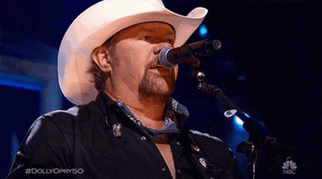 a man in a cowboy hat singing into a microphone on nbc
