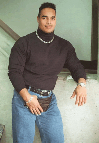 a man wearing a black turtleneck and blue jeans holds a wallet in his pocket
