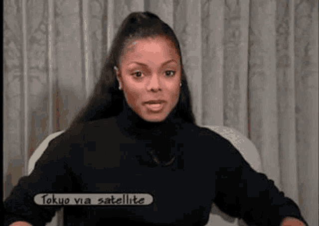 a woman is sitting in a chair wearing a black turtleneck sweater and looking at the camera .