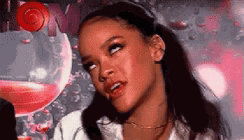 a close up of a woman making a funny face in front of a pink glass of wine .
