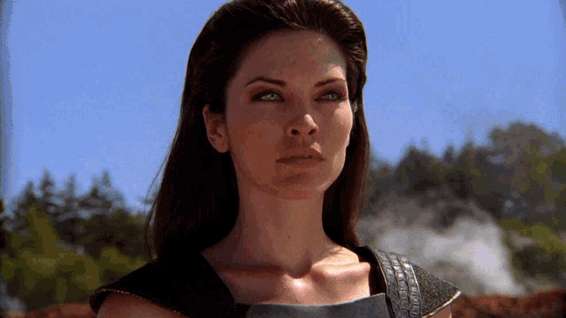 a close up of a woman 's face with a blue sky and trees in the background