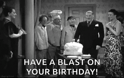 a group of people are standing around a table with a cake and a sign that says `` have a blast on your birthday ! ''