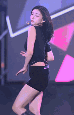 a woman in a black tank top and shorts is dancing