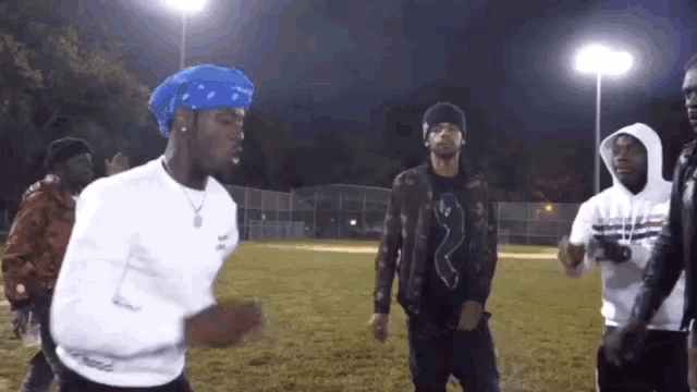 a group of young men are standing on a field at night .