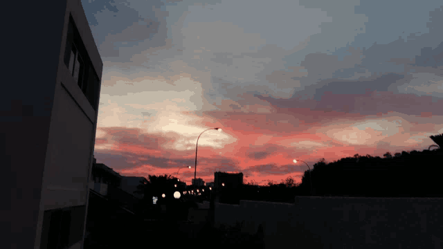 a sunset with a building in the foreground and a street light in the foreground