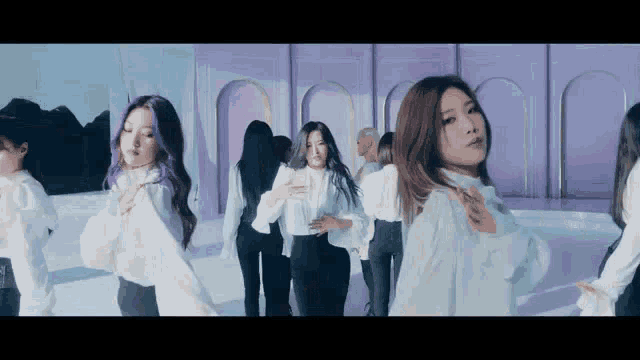 a group of women are dancing together in front of a purple wall .