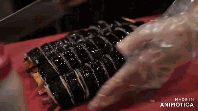 a person is cutting sushi on a cutting board with the words made in animatica on the bottom