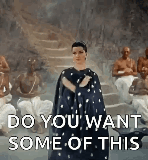 a woman in a cape is standing in front of a group of men and asking them if they want some of this .