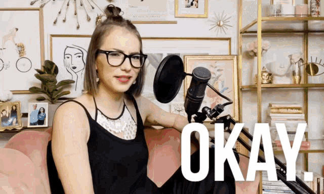 a woman sitting in front of a microphone with the word okay on the bottom right