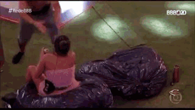 a man and a woman are sitting on top of a plastic bag on the floor .