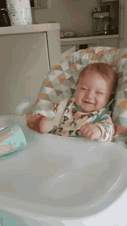 a baby is sitting in a high chair with a bottle in his hand .