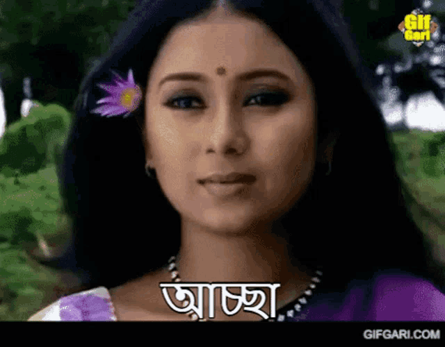 a close up of a woman 's face with a flower in her hair and the words " gifgari.com " on the bottom
