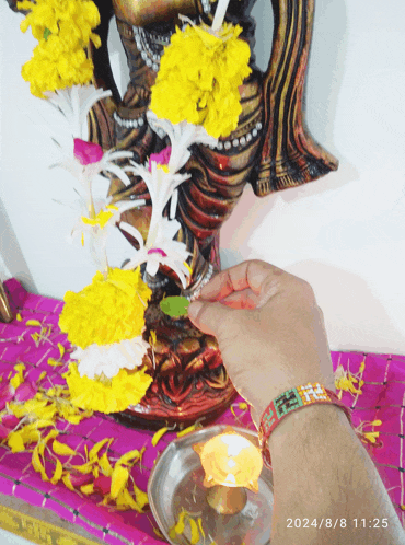 a person lighting a candle in front of a statue with the date 2024/8/8 11:25