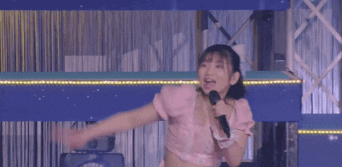 a girl in a pink dress holds a microphone in her hand