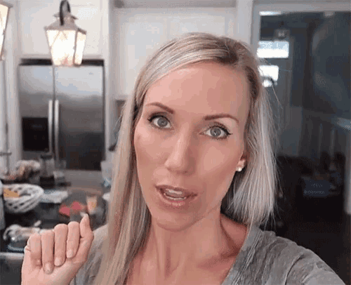 a woman in a kitchen with a refrigerator in the background