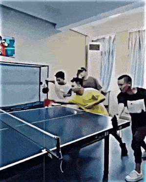a group of people playing ping pong in a room