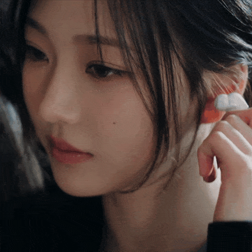 a close up of a woman 's face with a red earring in her left ear