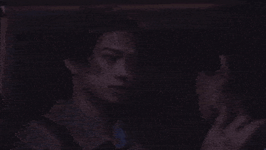 a man is touching another man 's ear in the dark