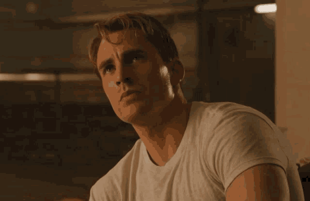 a man wearing a white t-shirt looks to the side