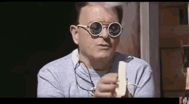 a man wearing sunglasses holds a piece of paper